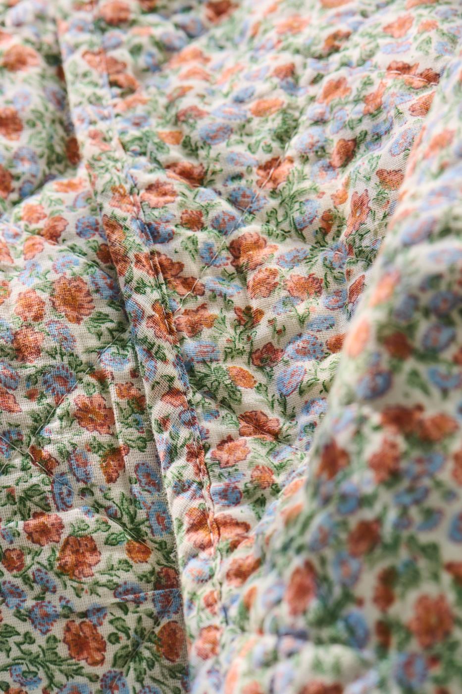 Quilt mit hellblauen und orangen Blumen